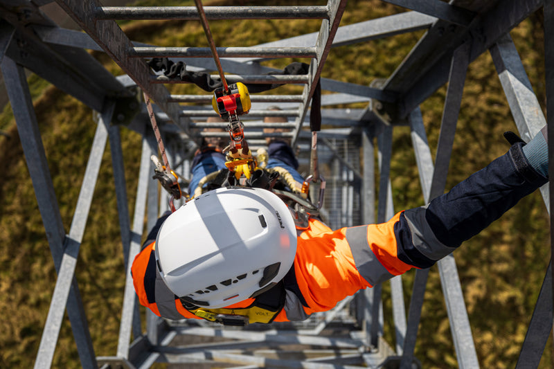Person in safety gear on a high-altitude work platform with a blurred natural background