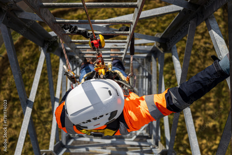 Person in safety gear working on a high structure with a blurred natural background