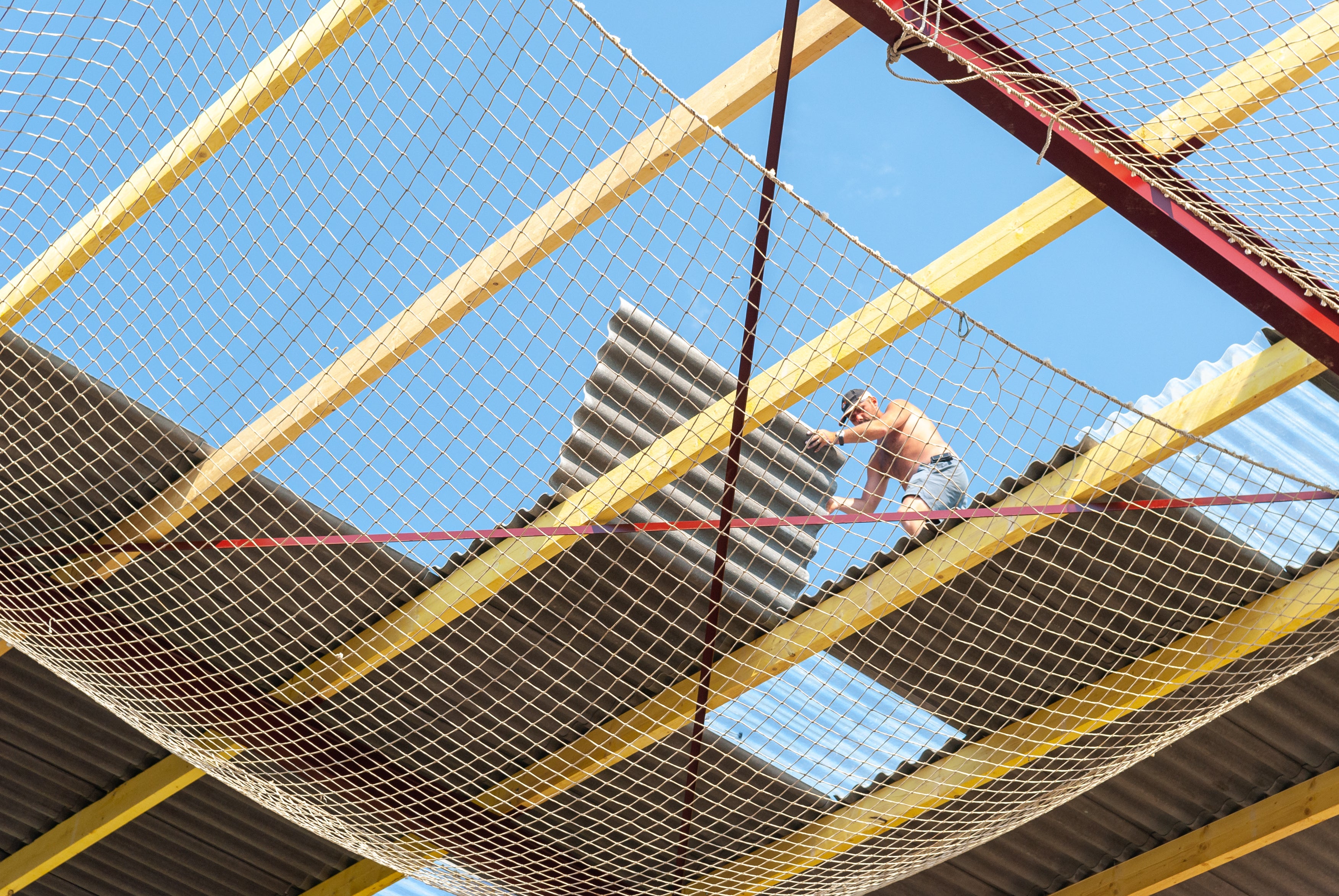 Person on a slackline above a building under construction with safety netting.